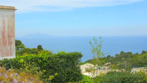 Con-Vistas-A-La-Costa-Y-Al-Mar-Con-Casas-Coloridas,-Agua-Azul-Y-Cielo-Despejado-En-El-Fondo-En-Capri,-Italia