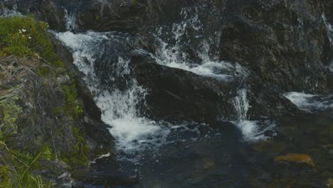 Una-Toma-Panorámica-Del-Agua-Que-Fluye-Sobre-Las-Rocas-En-Las-Montañas-De-Alberta-En-Canadá