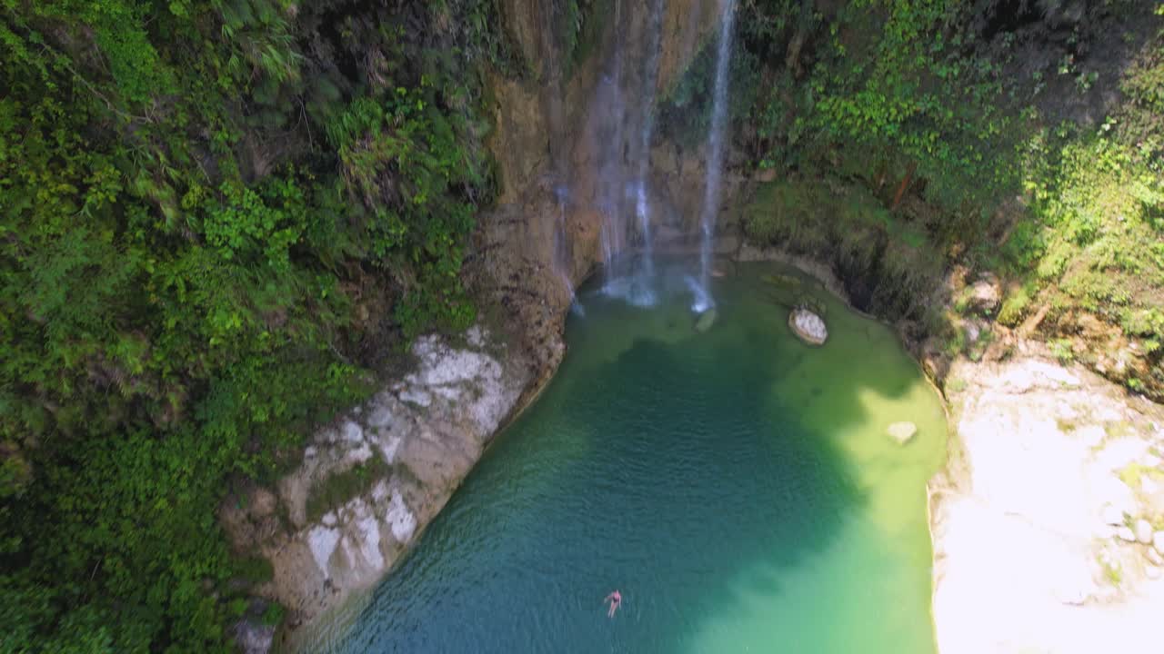 video de dron de 4k volando lejos de una mujer nadando en las cataratas de camugao en bohol, filipinas