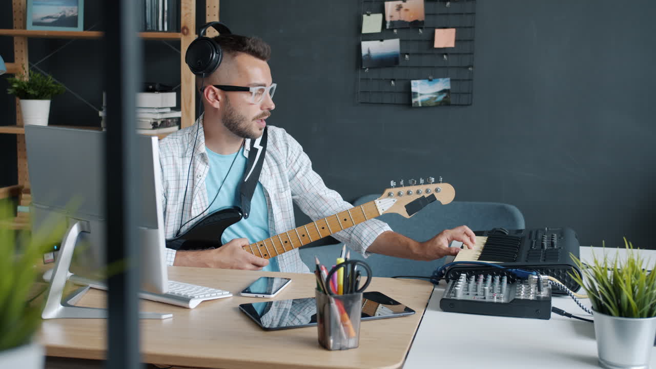 Musician Playing Guitar and Using Audio Mixer in Home Studio