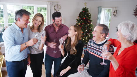 retrato de padres mayores con hijos adultos y amigos bebiendo champán mientras celebran la navidad juntos en casa