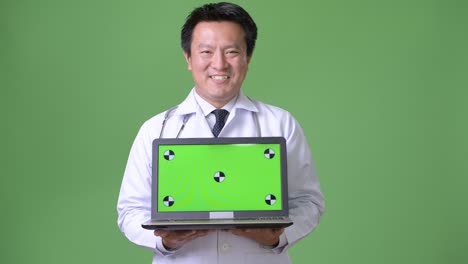 성숙한 일본인 남성, 초록색 배경의 의사