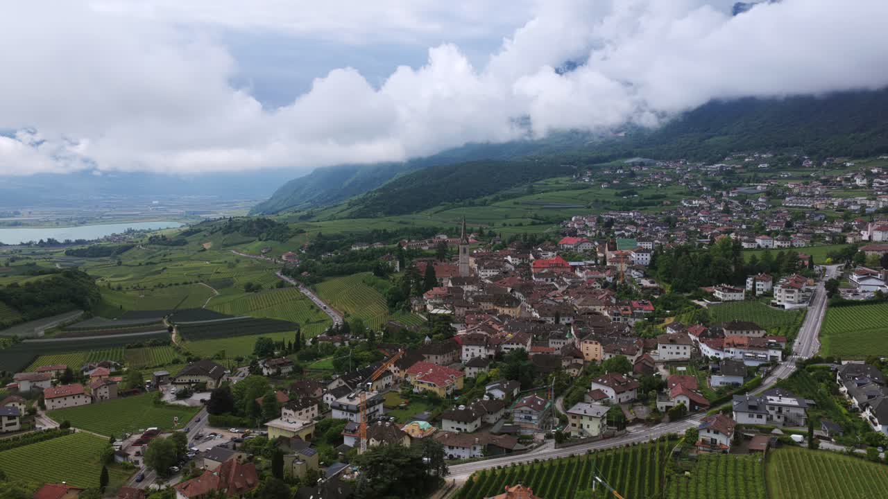 Aerial view of Caldaro sulla Strada del Vino, featuring the prominent Caldaro Parish Church amidst vineyards and mountains