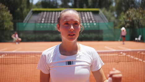 female tennis player wipes sweat on clay court after a match