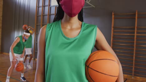 portrait of african american female basketball player with teammates in background