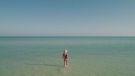 Good-looking-woman-in-bikini-with-perfect-body-walking-in-blue-shallow-water