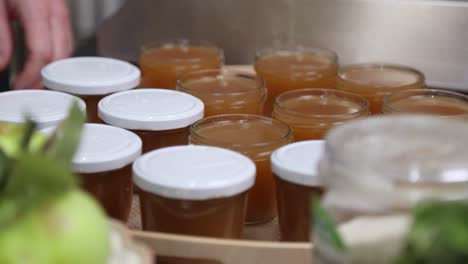 Covering-Small-Jars-Of-Apple-Jam-With-Lid---close-up