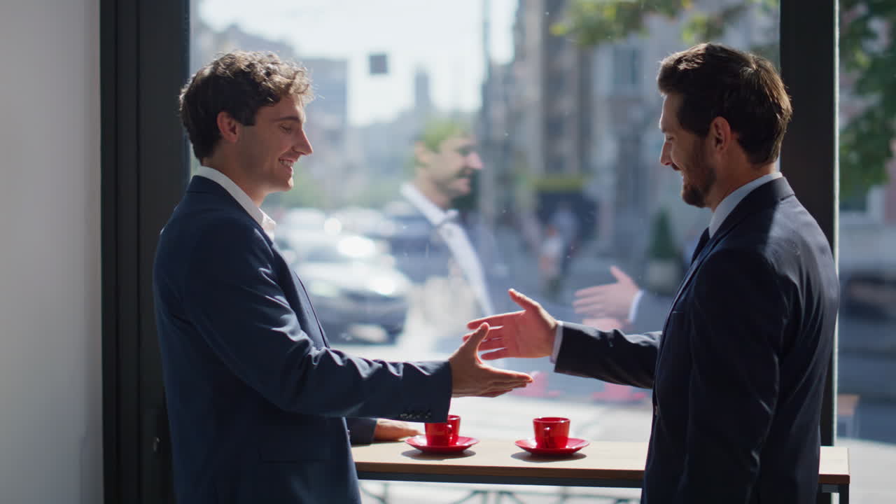 Two businessmen talking window cafe closeup. Partners making deal shaking hands