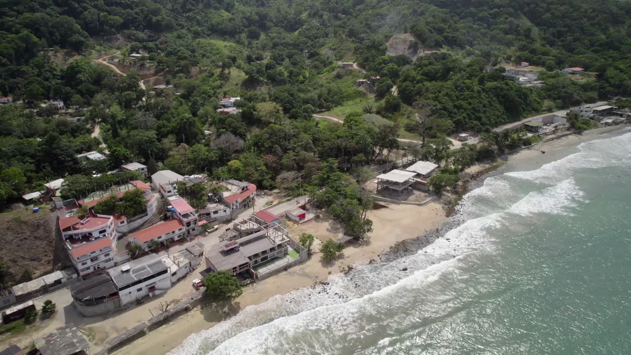A peaceful beach with traditional Caribbean homes in La Guaira, surrounded by green hills
