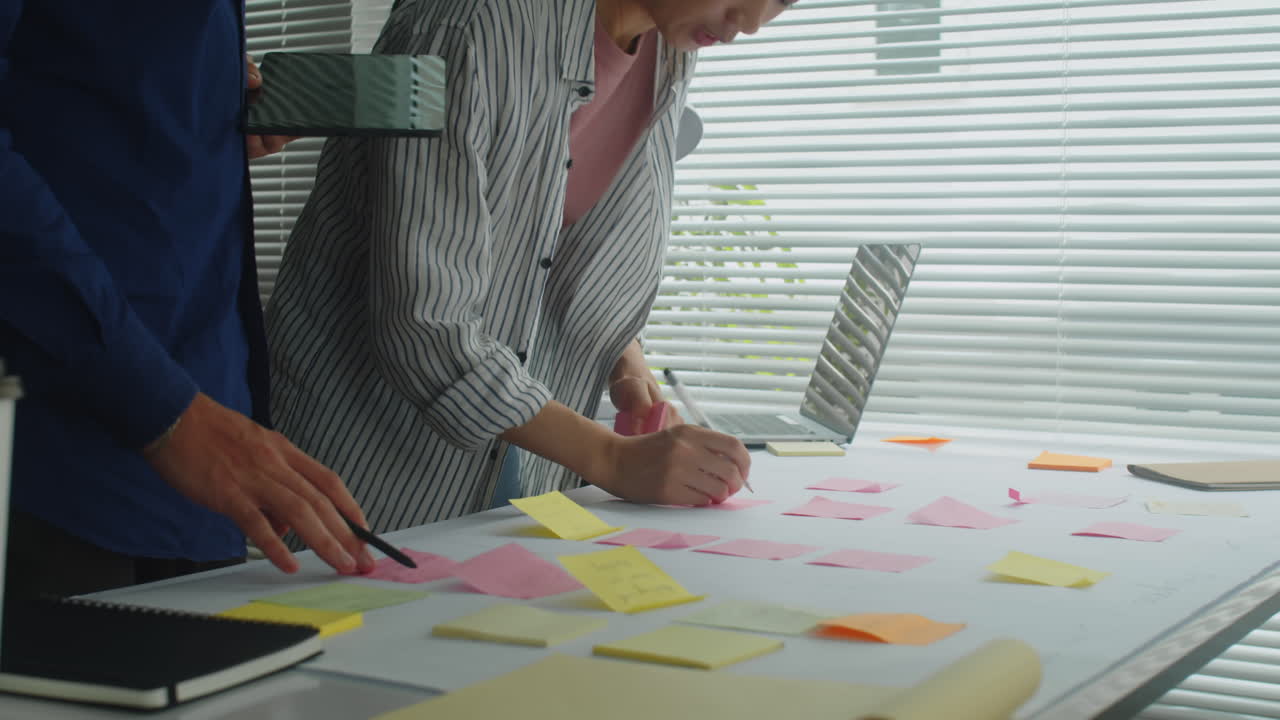 Couple of Colleagues Working on Project on Big Placard at Table