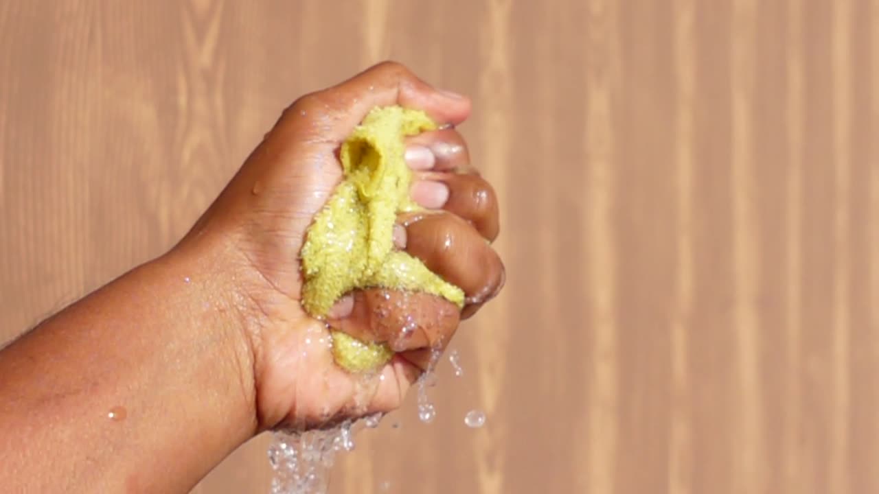 Hand squeezing water out of a sponge