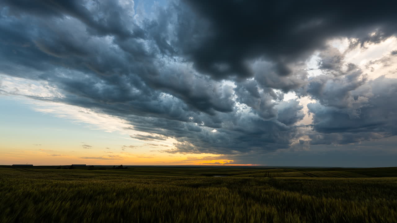 Contrasting colors and textures fill the sky as dark clouds drift across a colorful sunset
