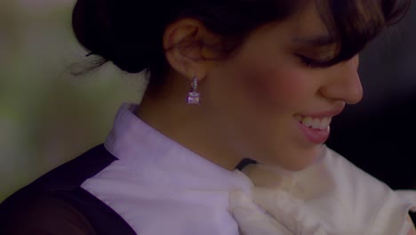 cinematic close up shot of a beautiful woman fixing her horse riding outfit while wearing diamond earrings and smiling, slomo, slow motion, close-up