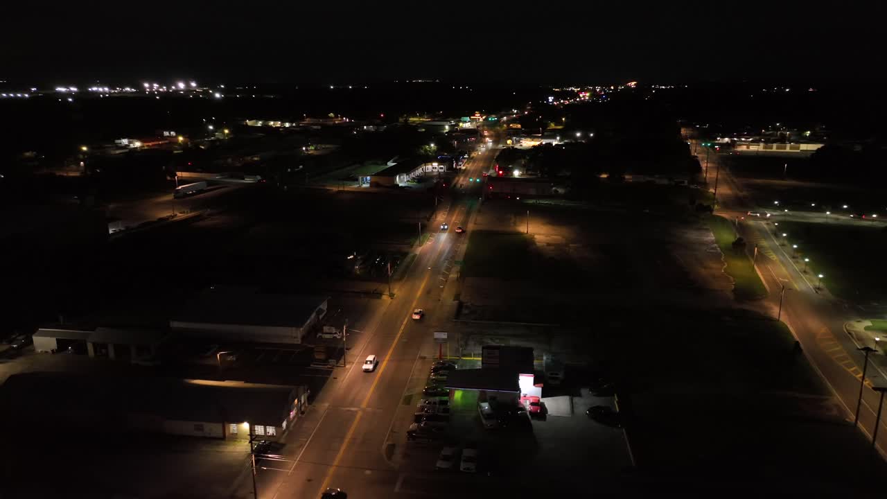 Driving cars on suburb road at night. American gas station and warm lighting lantern on intersection. Aerial top down. Florida, united states.