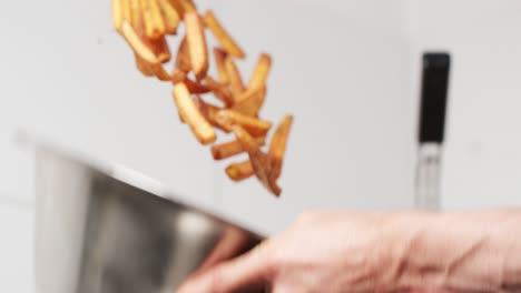 a portion of fries is thrown in the air, turned and tossed in condiments