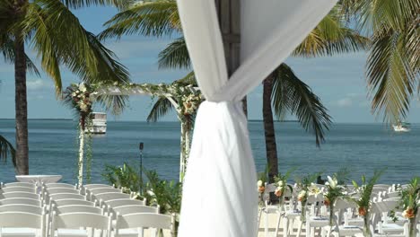 lento de izquierda a derecha panorámica del lugar de la boda decoración y flores asientos al aire libre playa de arena asientos de compromiso con mesas