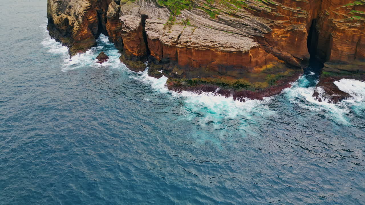 Foaming waves crashing rocky coastline aerial. Wild sea washing reef rock cliffs