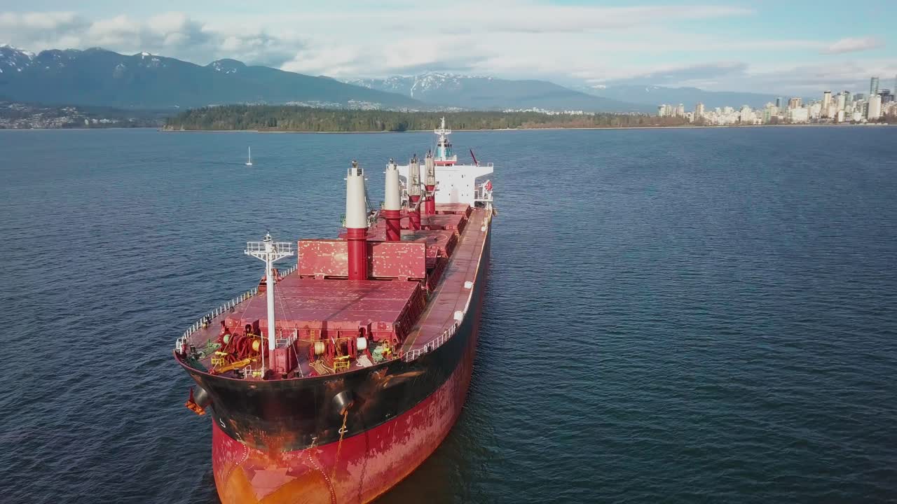 volando frente a un buque granelero anclado en la entrada de burrard cerca de vancouver, bc, canadá