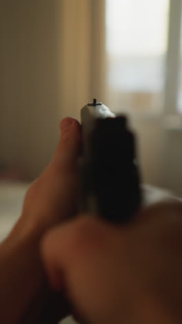 imágenes de una persona caminando cautelosamente por habitaciones iluminadas por el sol con una pistola cargada, apuntando mientras se acercan a un dormitorio