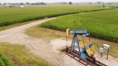 a pumpjack on the middle of the corn field near mount pleasant, isabella county, michigan - aerial static shot