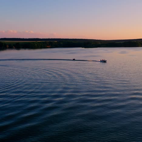 boat sailing at sunset. evening river landscape on industrial factory background. motor boat pulling small boat on water. summer vacation. aerial view.