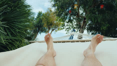 a man is resting in a hammock a first-person view in the frame only the legs are visible 4k video