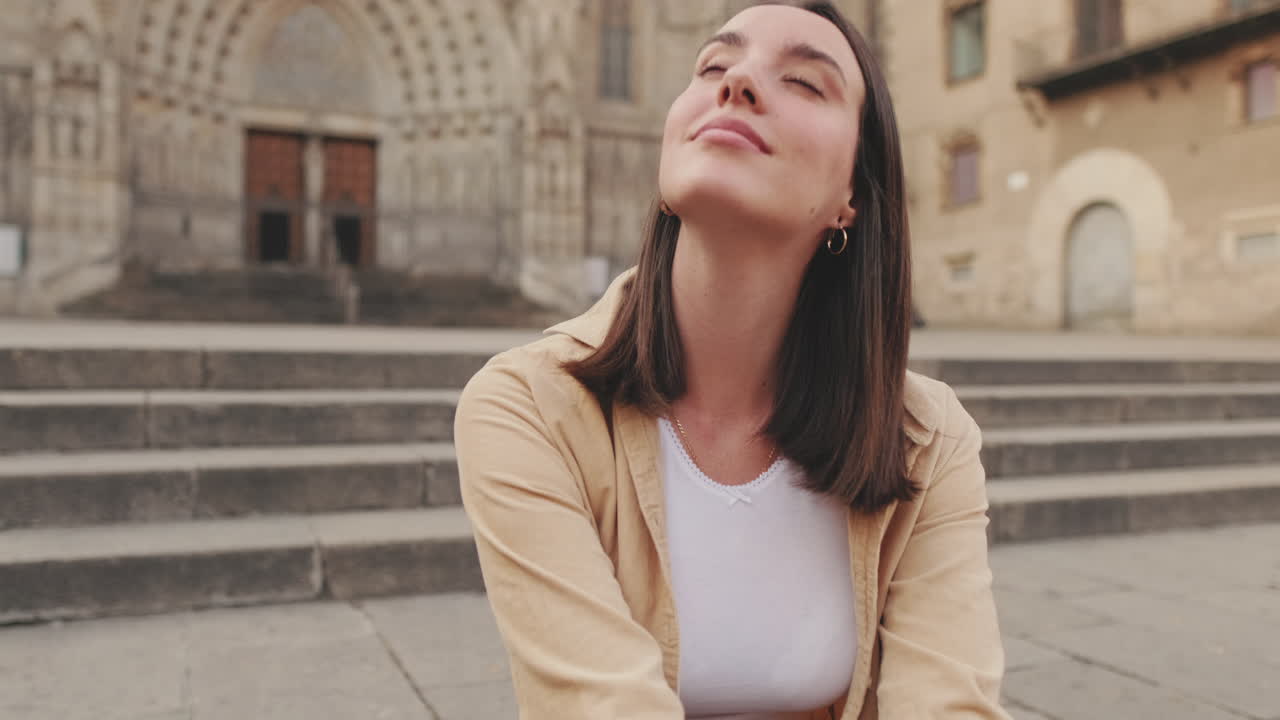 Giovane donna seduta sui gradini davanti a un'antica cattedrale