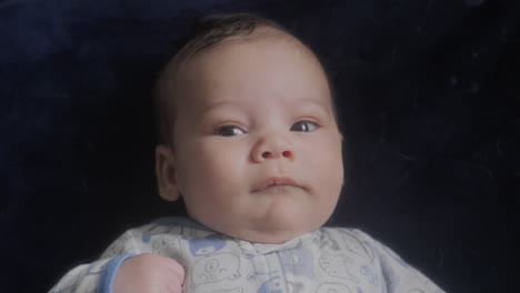 portrait of baby boy laying on his back looking up at the camera