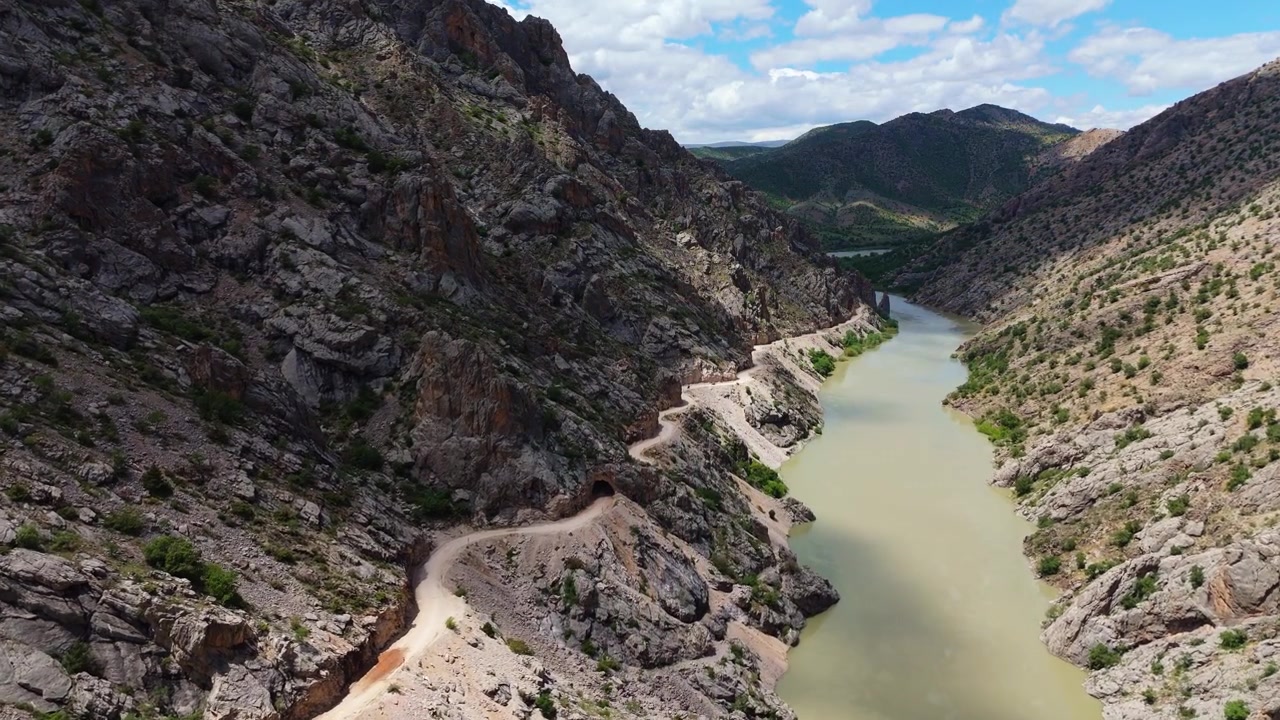 Veduta aerea del fiume Karasu con la leggendaria Strada di Pietra intagliata a mano visibile sulla scogliera con un tunnel scavato nella roccia nel Canyon a Kemaliye, Turchia