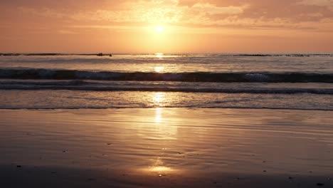 golden sunrise reflects on the sandy beach as waves ripple