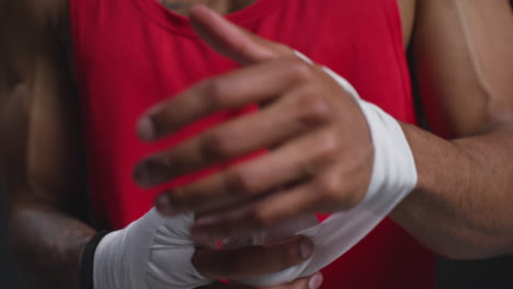 close-up em tempo real de um boxeador masculino envolvendo as mãos com bandagens protetoras antes de uma partida de boxe ou sessão de treinamento 1