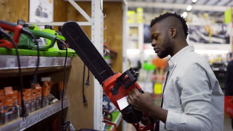 Concentrated-man-examining-chainsaw-at-a-hardware-store