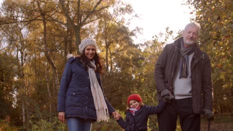 multi generation family take dog for walk in fall landscape