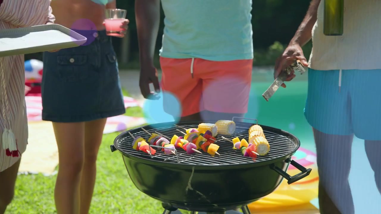 Donne che offrono spiedini, uomini che girano il mais al barbecue a bordo piscina per una cottura uniforme con bokeh che mostra il cibo