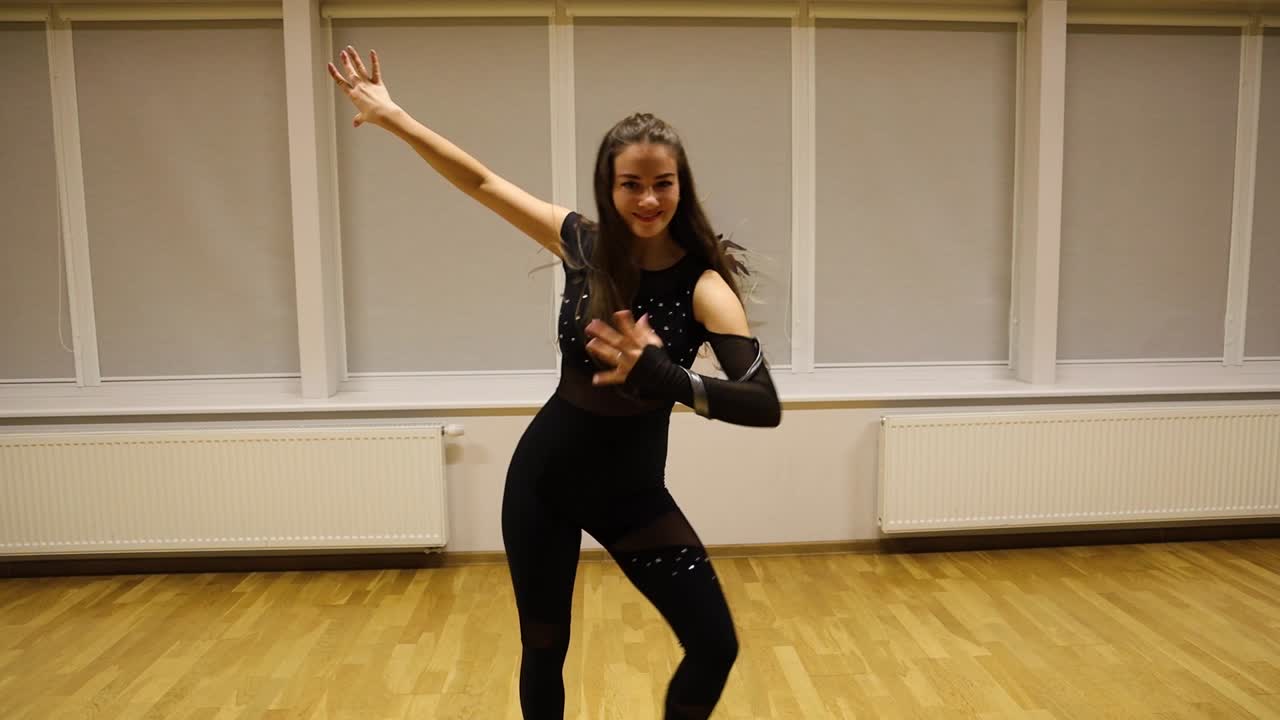 Beautiful young woman smiling at the camera while performing a modern dance routine in an empty studio