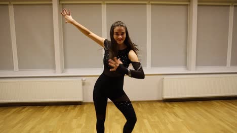 beautiful young woman smiling at the camera while performing a modern dance routine in an empty studio