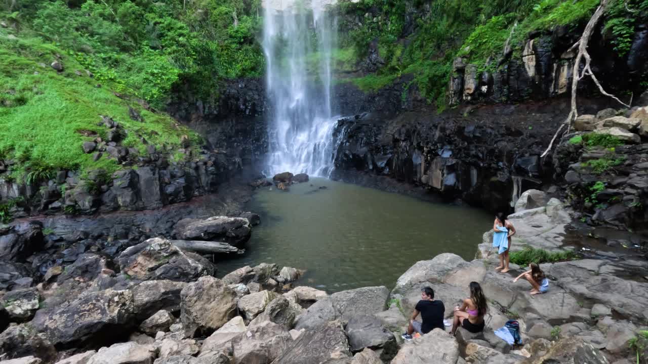 울창 한 숲 에서 폭포 를 즐기는 사람 들