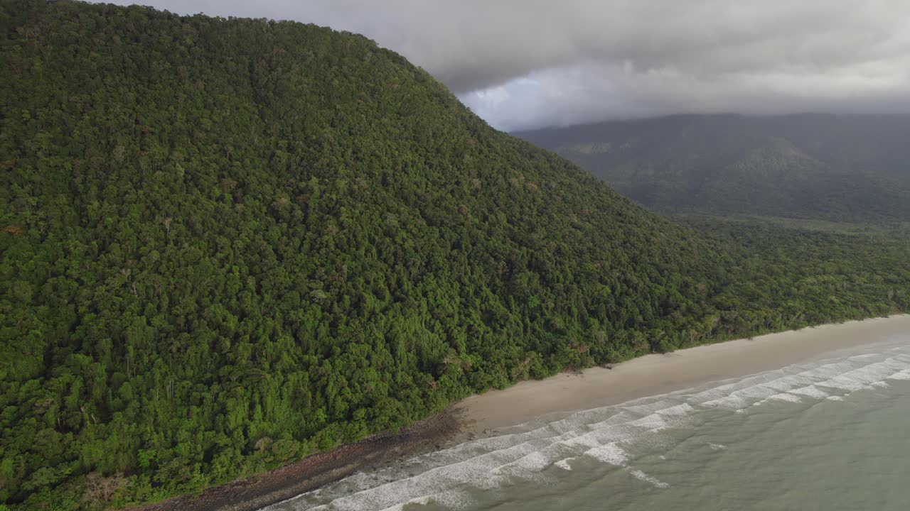 montañas boscosas que se elevan sobre una playa tranquila en el parque nacional daintree, norte de queensland, australia