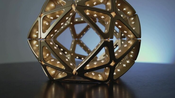 Camera shifting causing gold geometric sculpture rotating on glossy tabletop, revealing inner core