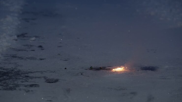 Adult lights tiny ground firework on snow using match, weak sparks and minimal effect