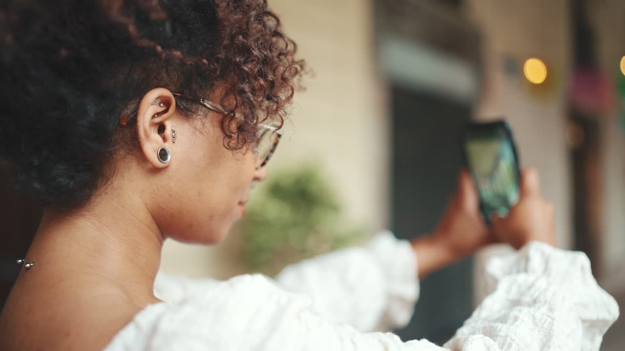 Woman with curly hair taking a photo with her phone