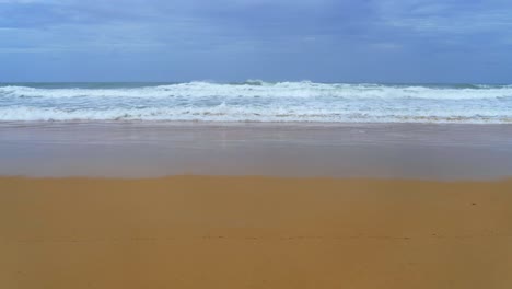 landscapes view of waves breaking on beach sand and the sky on a stormy rainy season