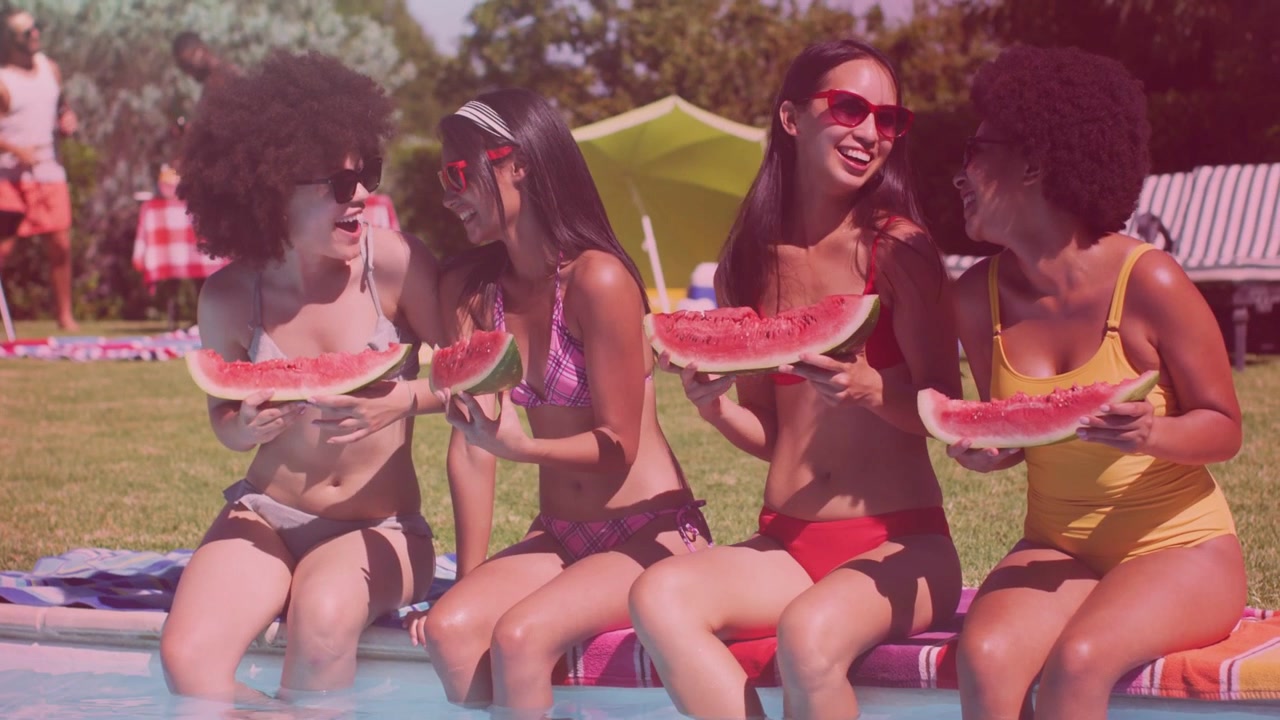 Vier vrouwen zitten aan het zwembad, delen watermeloen, kletsen, lachen en gebaren, met advertenties van vallende hartjes.