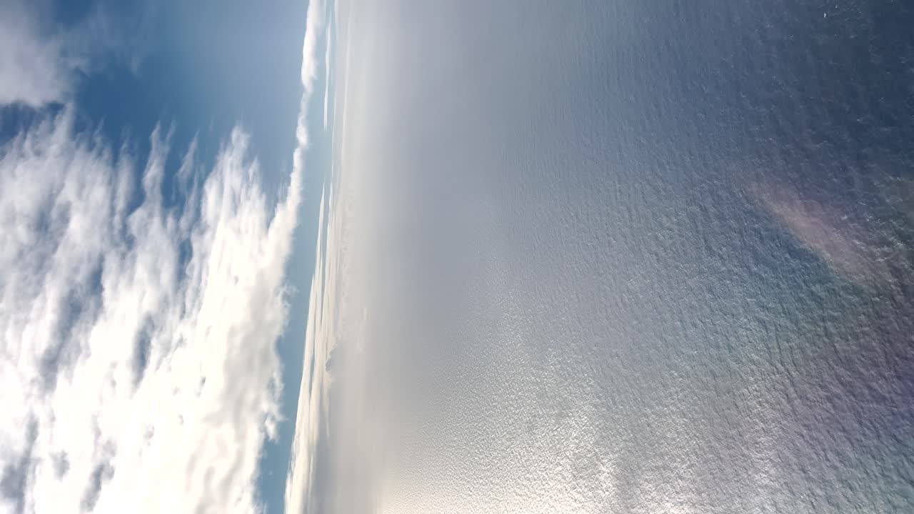 Aerial view of blue sky and ocean from a plane in clear weather, vertical