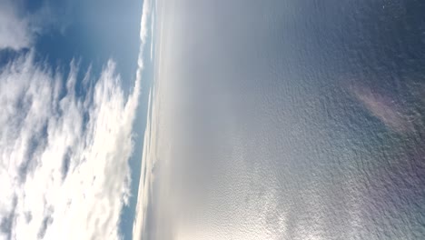 Aerial-view-of-blue-sky-and-ocean-from-a-plane-in-clear-weather,-vertical