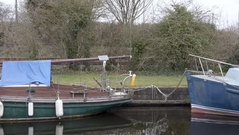 Small-sailboats-moored-on-narrow-rural-countryside-canal-waterscape