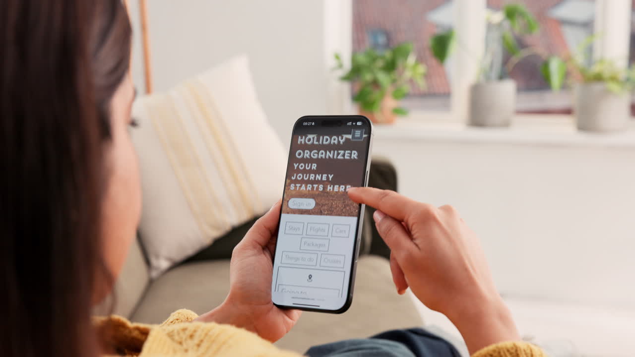 A woman using a travel booking app on her smartphone at home