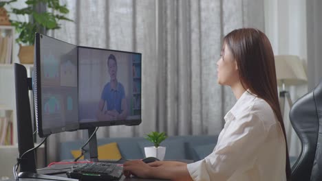 side view of asian female automotive designer having a meeting with a woman while working on 3d model of ev car on the desktop computers in the studio