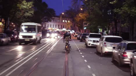 tipo grande en motocicleta haciendo acrobacias montando en la ciudad de pie en el asiento en la ciudad nocturna