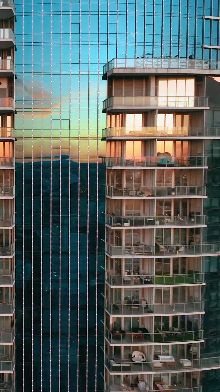 Glass facades of a skyscraper building with a reflection of a sunset landscape. Downtown Miami Florida. Aerial view. Vertical video